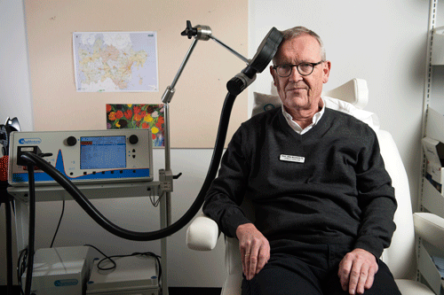 Ledende overlæge Poul Erik Buchholtz demonstrerer her behandlingen med magnetstimulation. Magnetfeltet dannes i den glasfiberbeklædte strømspole, som bringes i kontakt med patientens hoved i det område af hjernen, man ønsker at påvirke. Foto: Bo Amstrup