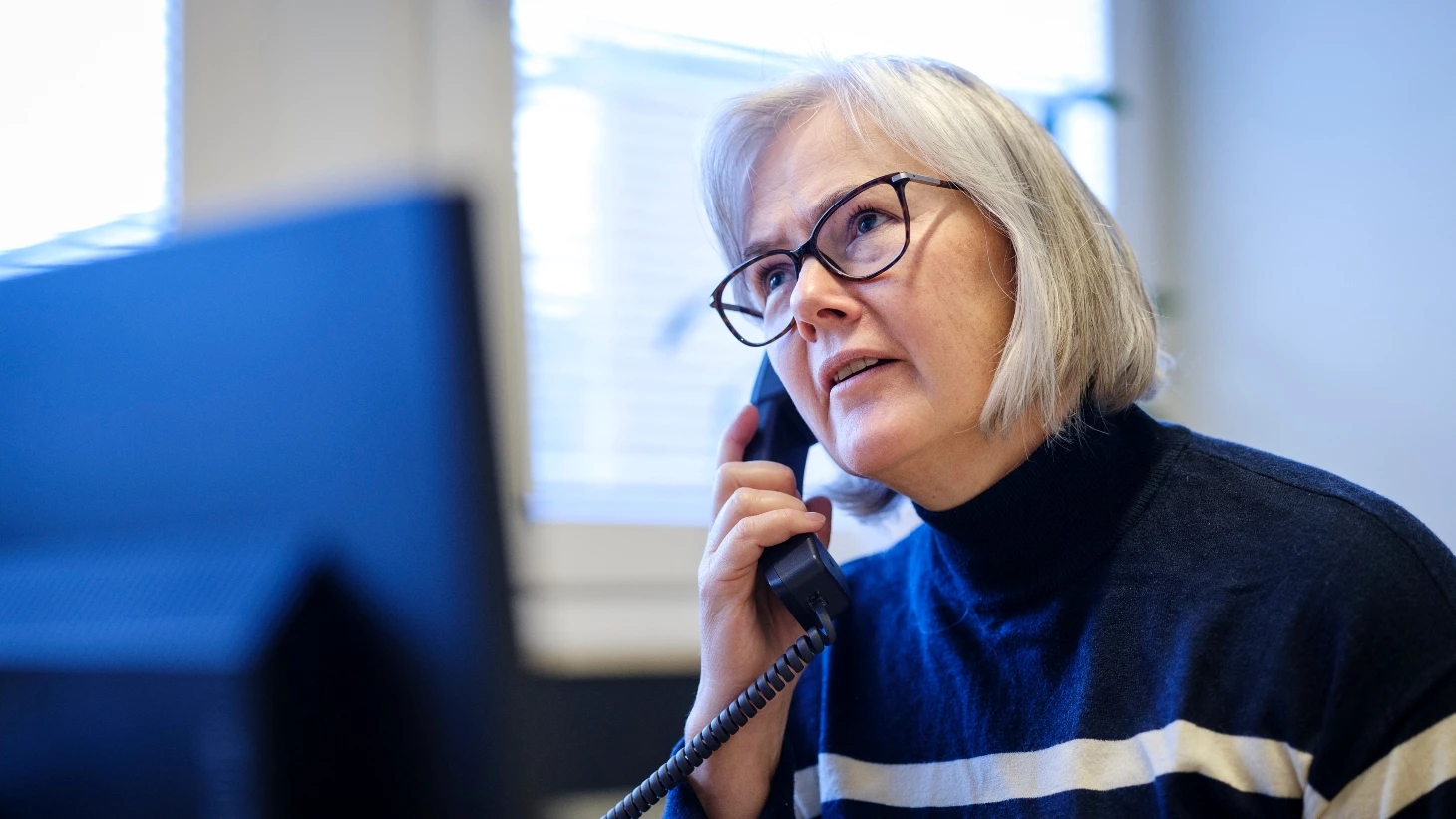 Socialrådgiver sidder ved sin computer og taler i telefon